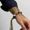 Side close-up of a man wearing the Pangu inspired After the Divide bracelet (12mm) showing the colorful tassel cord, gold charm and mixed beads