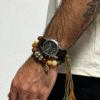 Man styling the Pangu inspired After the Divide bracelet (12mm) with a watch, featuring mixed material beads, a colorful tassel cord and gold charm details