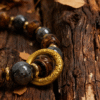 Close-up of After the Flood agate bracelet inspired by Gonggong, featuring 10mm agate beads, gold-tone ring detail, and natural wood background with autumn leaves