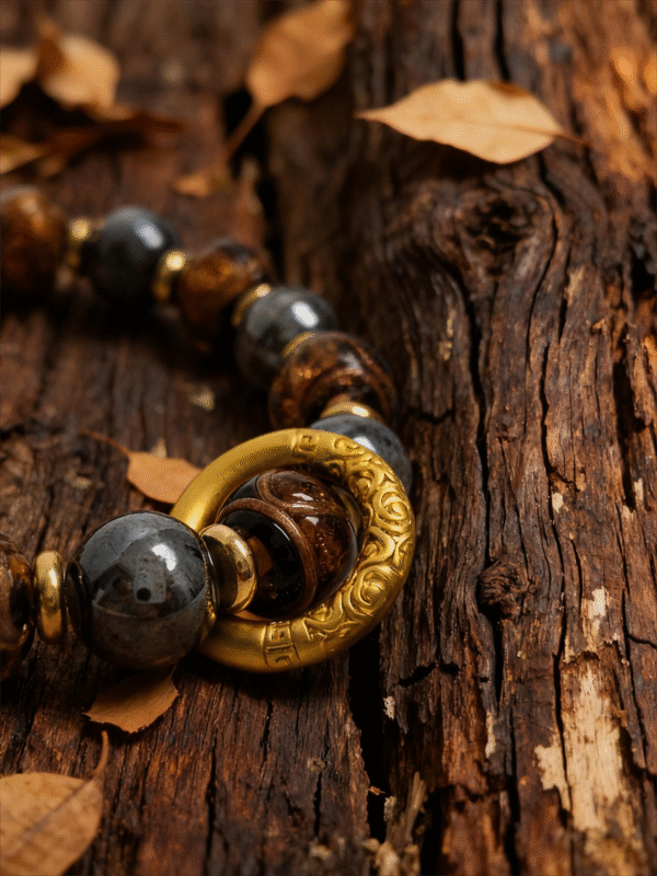 Close-up of After the Flood agate bracelet inspired by Gonggong, featuring 10mm agate beads, gold-tone ring detail, and natural wood background with autumn leaves