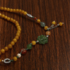Amber Dawn Genesis Bracelet – Pangu Edition (5mm) featuring golden amber beads, green jade motif, and metal accents photographed on a dark wooden surface