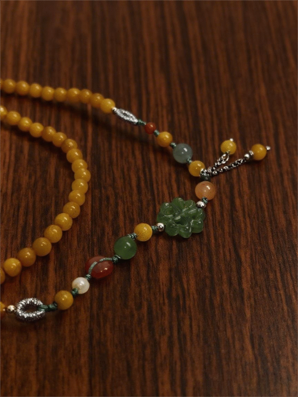 Amber Dawn Genesis Bracelet – Pangu Edition (5mm) featuring golden amber beads, green jade motif, and metal accents photographed on a dark wooden surface