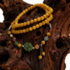 Amber Dawn Genesis Bracelet – Pangu Edition (5mm) with golden amber beads and green jade charm displayed on a natural wooden background