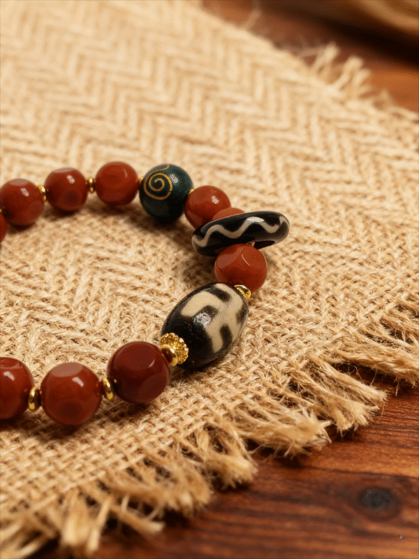 Bound Resolve Red Agate Bracelet 10mm – Xingtian Inspired Close-Up Detail on Burlap Background Close-up of the Xingtian inspired Bound Resolve red agate bracelet (10mm) featuring faceted red beads, patterned accent beads and gold spacers on a burlap background
