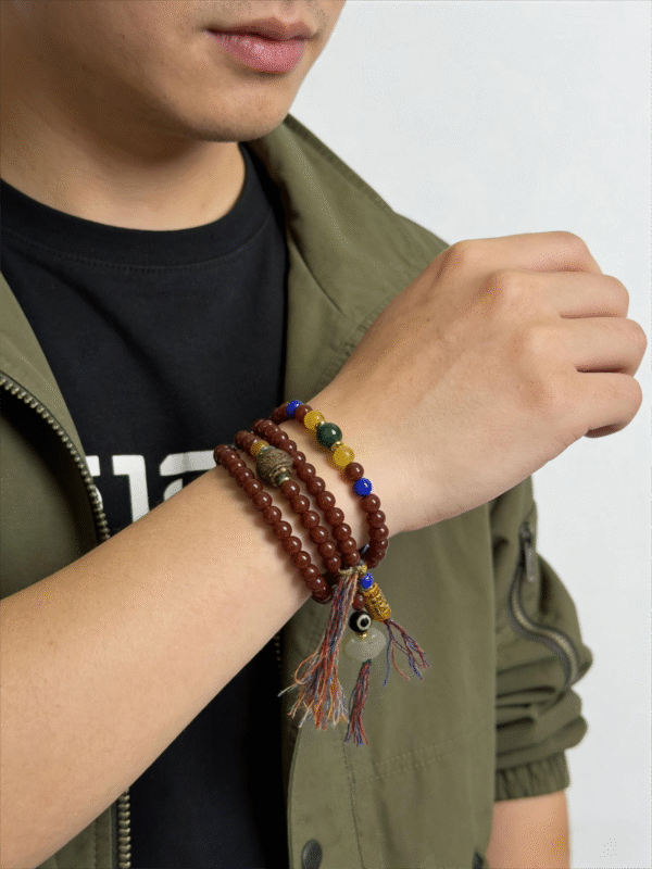 Bound Resolve Red Agate Bracelet 10mm – Xingtian Inspired Men’s Styling Shot with Watch Men wearing the Xingtian inspired Bound Resolve red agate bracelet (10mm) in a multi-wrap style with colorful accent beads and tassel charms on a clean white background
