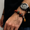 Bound Resolve Red Agate Bracelet 10mm – Xingtian Inspired Men’s Styling Shot with Watch Close-up of a man styling the Xingtian inspired Bound Resolve red agate bracelet (10mm) with a watch, featuring red agate beads, black and white pattern beads and a wooden charm