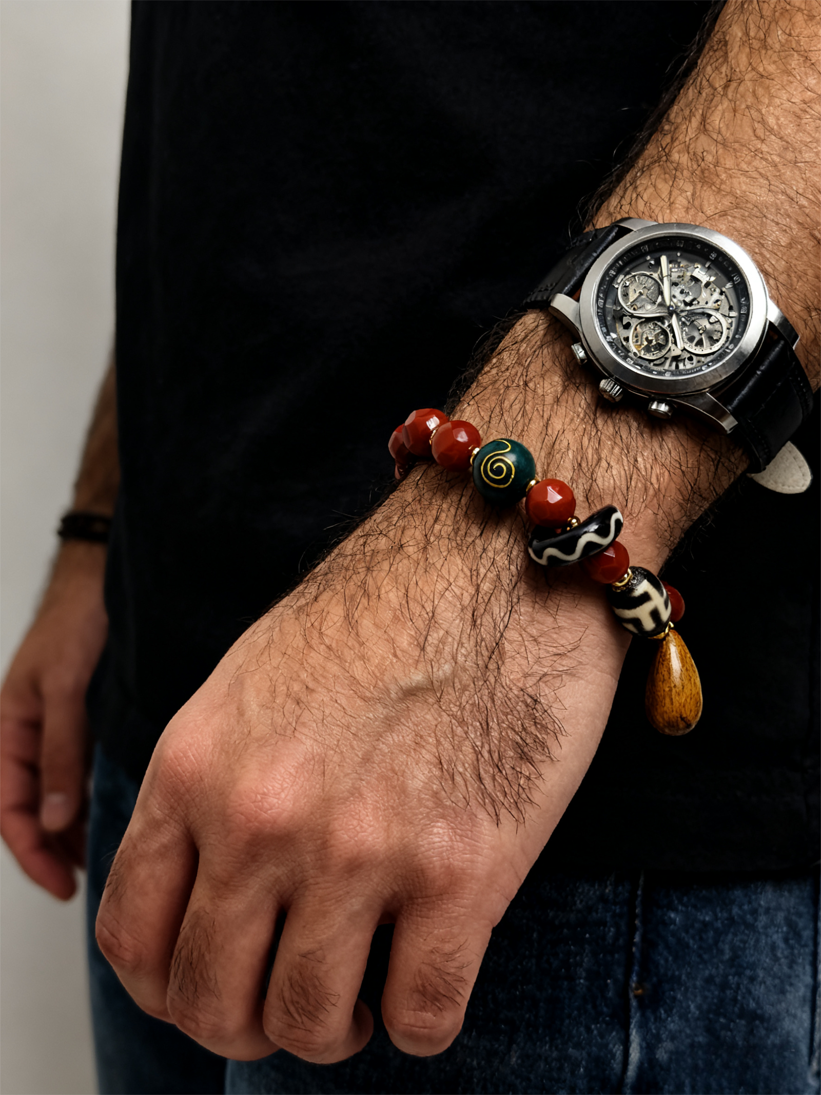 Bound Resolve Red Agate Bracelet 10mm – Xingtian Inspired Men’s Styling Shot with Watch Close-up of a man styling the Xingtian inspired Bound Resolve red agate bracelet (10mm) with a watch, featuring red agate beads, black and white pattern beads and a wooden charm