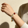 Chang’e Inspired Lunar Stillness Agate Bracelet – Elegant Everyday Wear Close-up of the Lunar Stillness Agate Bracelet on a woman’s wrist, highlighting translucent white agate beads, green details, and a red center stone