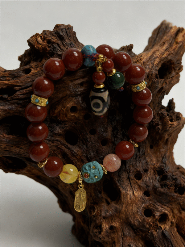 Crimson Fury & Turquoise Totem Bracelet from the Xingtian Myth Collection, featuring polished red cinnabar beads, deep green jade stones, a carved turquoise totem centerpiece, and gold-tone spacer accents. The 10mm beaded bracelet is displayed on a textured natural wood background, highlighting its bold mythological design, handcrafted details, and rich contrast of red, green, and turquoise tones.