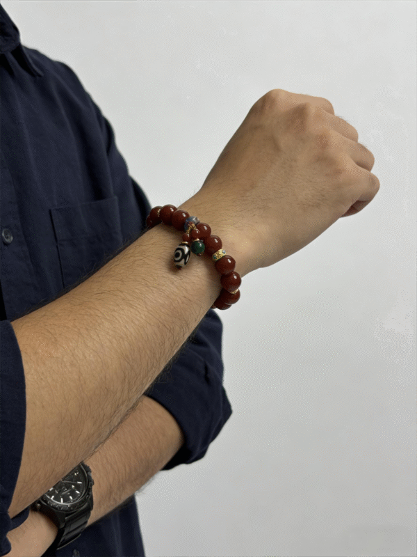Side view of a man’s wrist adorned with the crimson agate and turquoise totem bracelet, blending traditional mythological elements with modern masculine styling.