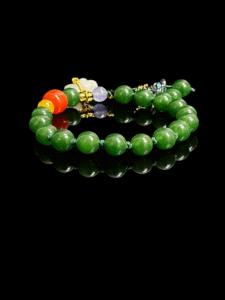 Studio product shot of the Shennong inspired Crimson Herbfruit Jade bracelet, crafted with polished 10mm deep green jade beads, accented by vivid red and golden agate elements, translucent herbal-toned stones, and refined gold spacers, arranged on a glossy black background to highlight the rich luster, natural vitality, and ancient herbal symbolism rooted in Eastern mythology.