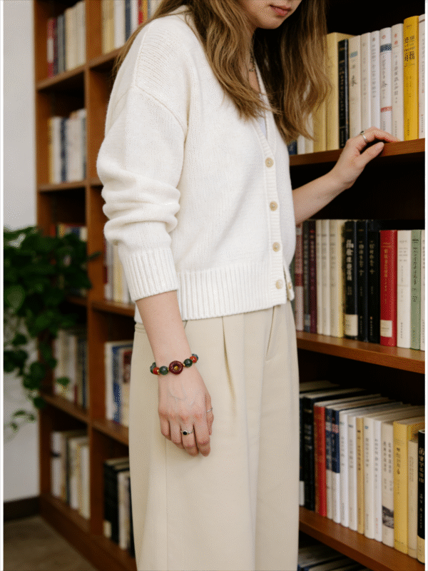 Woman wearing the Crimson Seal & Jade Grove Bracelet – Shennong Edition (10mm) in an indoor setting, featuring green jade beads and a carved crimson seal focal bead, blending traditional Eastern symbolism with modern everyday elegance