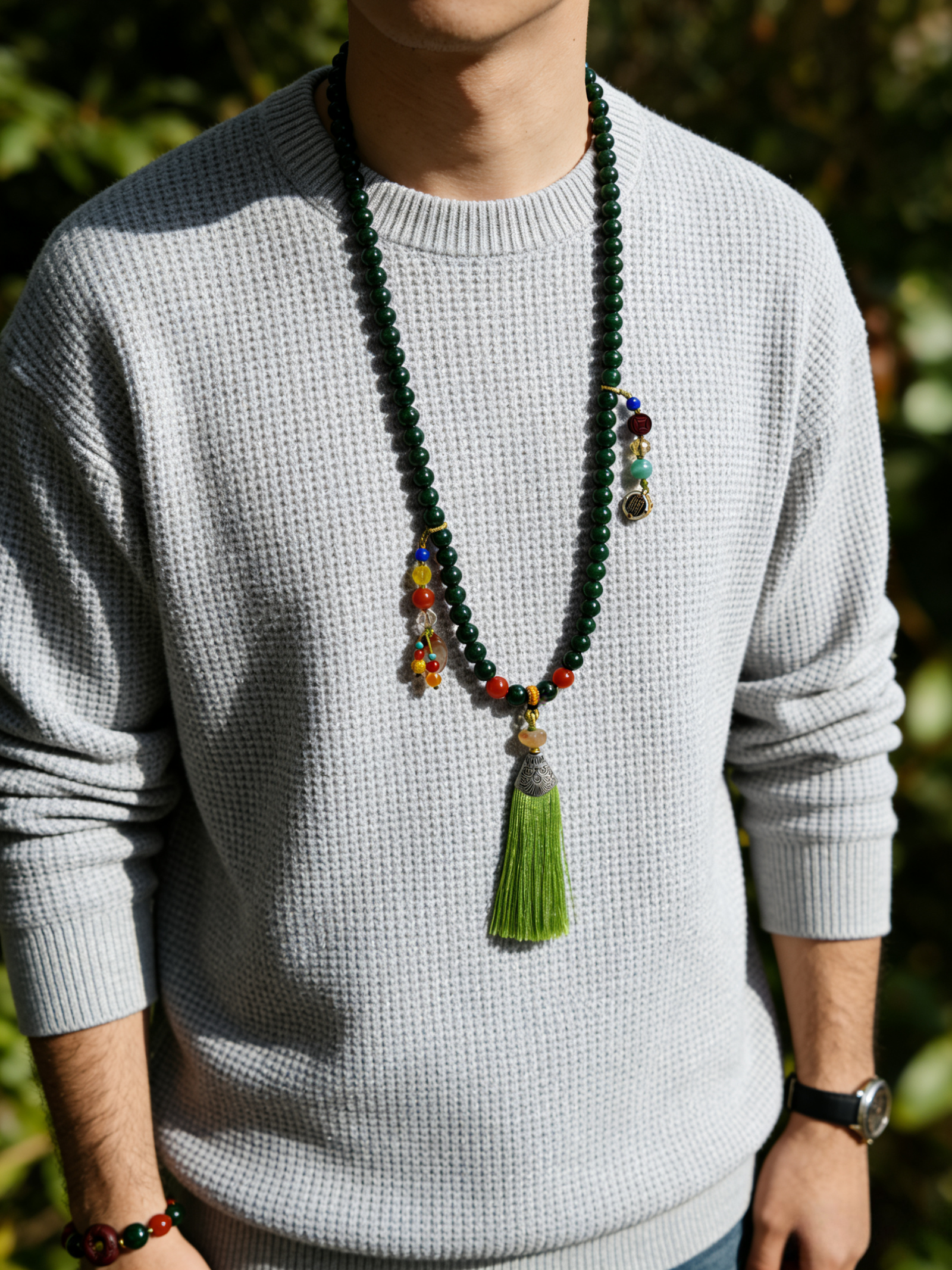 Man wearing the Shennong inspired Herbal Way bracelet (8mm) as a necklace, featuring dark green beads, colorful accents and a green tassel pendant in outdoor light