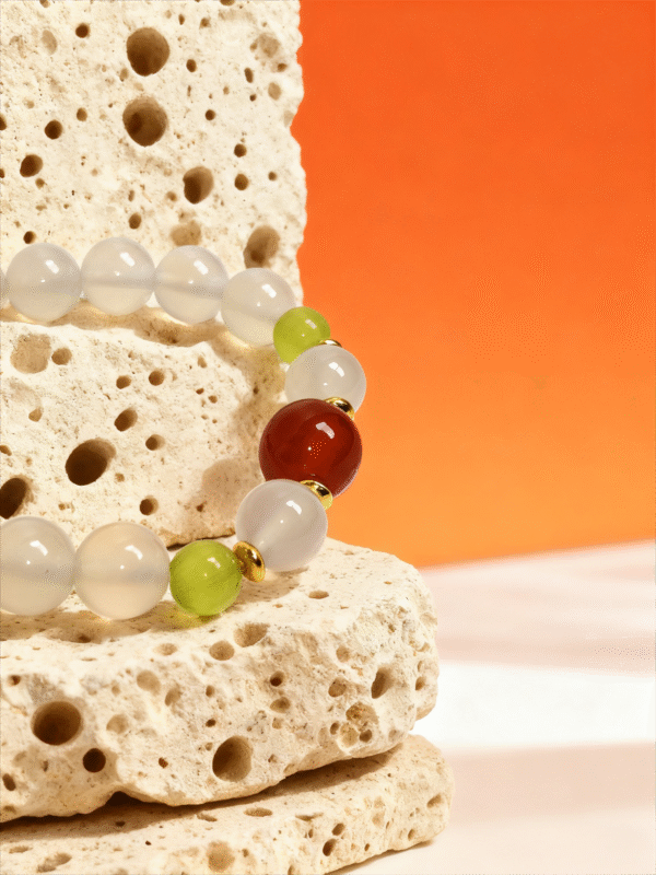 Lunar Stillness Agate Bracelet – Chang’e Inspired Detail on Stone Close-up of Lunar Stillness Agate Bracelet – Chang’e Inspired, featuring milky white agate beads with green accents and a red focal bead, displayed on textured stone background