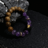 Full view of the Nüwa inspired Mother of Earth bracelet (11mm) with purple translucent beads and natural wood beads on a dark stone background