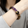 Close-up of the Nüwa inspired Mother of Earth bracelet (11mm) showing purple translucent beads, wood beads and gold spacer details
