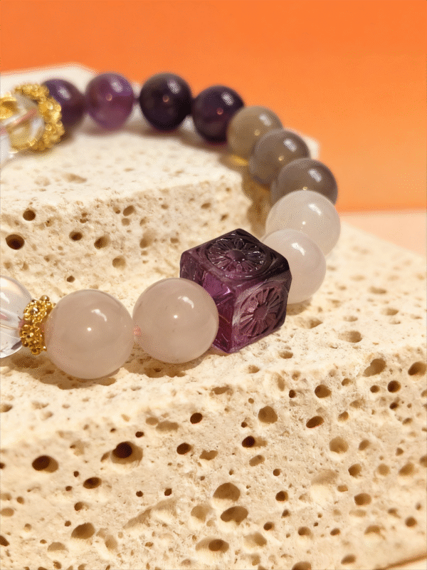 Nüwa Inspired Settled Order Bracelet – Purple Agate Detail Close-up of the Settled Order Bracelet inspired by Nüwa, highlighting the carved purple agate cube and smooth white gemstone beads on a stone surface