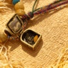 Close-up of Pangu inspired bone-agate bracelet featuring an opening relic charm box, yellow agate beads and braided cord on woven straw background