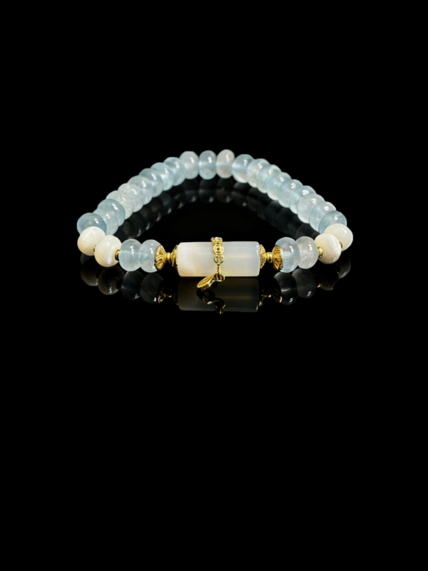 Product photo of the Jingwei inspired Quiet Oath aquamarine bracelet (6mm) with light blue beads, white accents and gold details on a black background