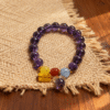11mm purple translucent beaded bracelet with yellow red blue accent beads and charm on linen and wood background