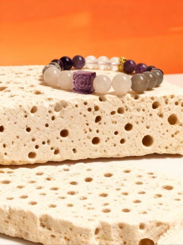 Settled Order Bracelet – Nüwa Inspired on Stone Display Settled Order Bracelet inspired by Nüwa, featuring purple agate centerpiece and translucent gemstone beads, displayed on textured stone against a warm orange background