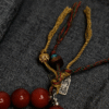 Detail of Unyielding Core Red Agate Bracelet Xingtian Inspired featuring hand tied cord and symbolic charm