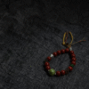 Unyielding Core Red Agate Bracelet Xingtian Inspired displayed on dark fabric background with green center stone