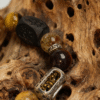 Close-up of Watchful Relic Gonggong inspired agate bracelet (12–15mm), featuring mixed gemstone beads and engraved metal charm, photographed on natural wood texture background