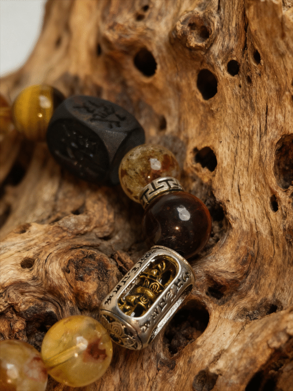 Close-up of Watchful Relic Gonggong inspired agate bracelet (12–15mm), featuring mixed gemstone beads and engraved metal charm, photographed on natural wood texture background