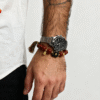 Man wearing Xingtian's Scarlet Agate Bracelet with red agate beads, gold accents and tassel, paired with a stainless steel watch