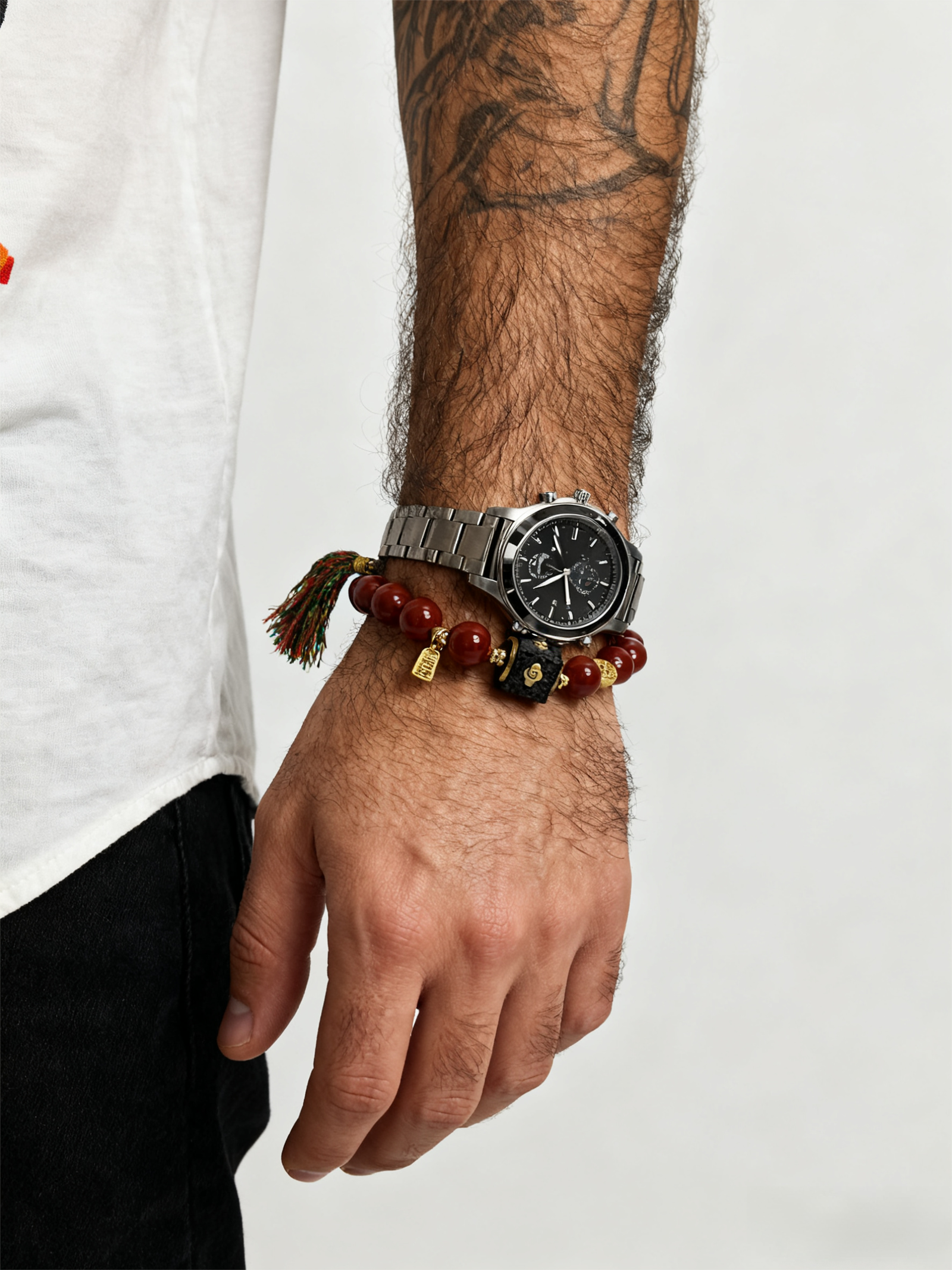 Man wearing Xingtian's Scarlet Agate Bracelet with red agate beads, gold accents and tassel, paired with a stainless steel watch