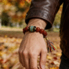 Close-up of Bound Resolve Red Agate Bracelet Xingtian Inspired 10mm on men’s wrist in autumn outdoor setting
