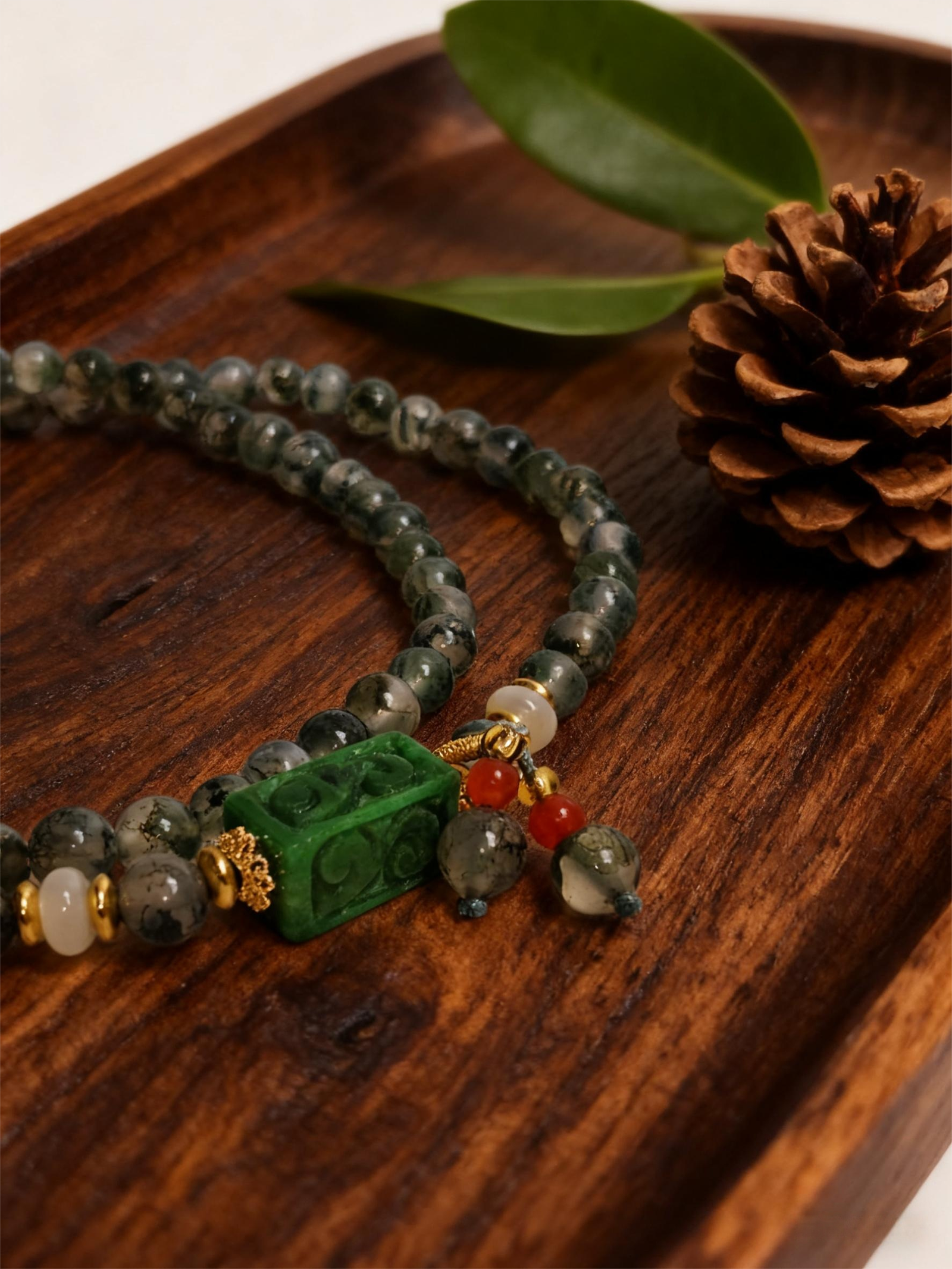 Close-up of Harmonizing Green Agate Bracelet Shennong Inspired 6mm featuring carved green agate centerpiece and natural stone beads on wooden tray