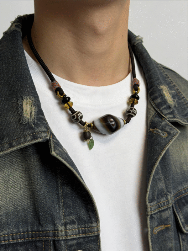 Model wearing Gonggong inspired turbulent layered agate and dzi necklace on neck
