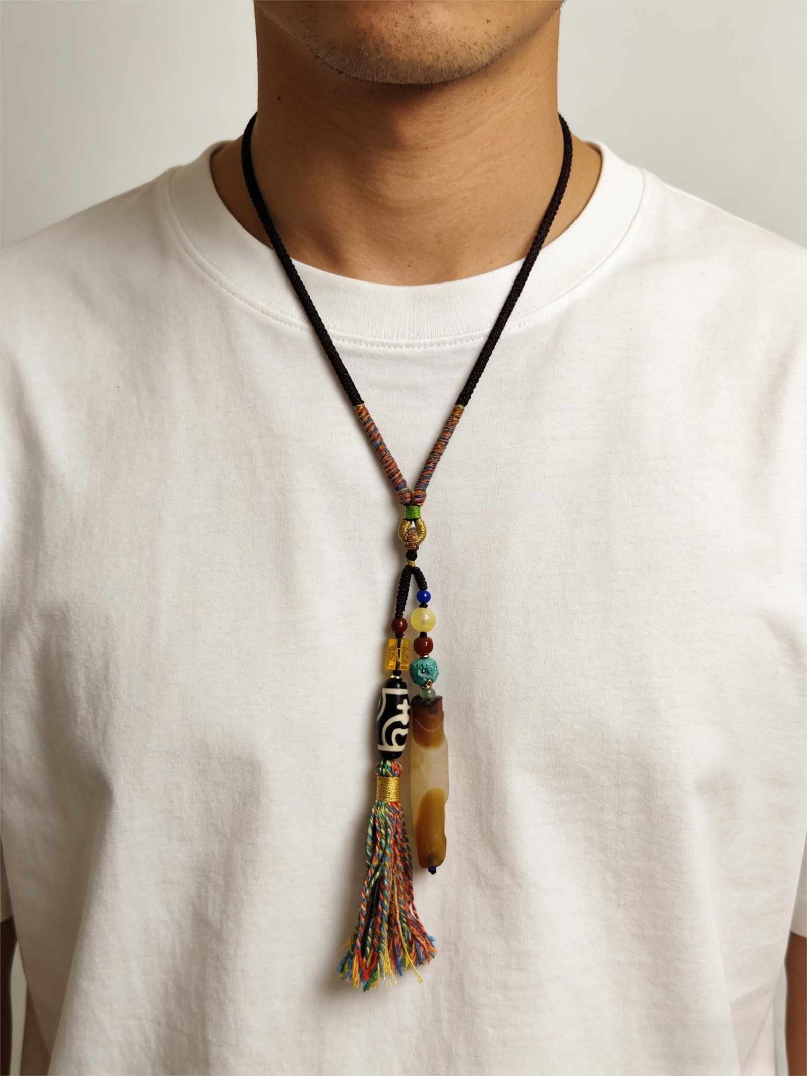 Primordial Layered Agate & Dzi pendant necklace worn over a white T-shirt, showcasing natural agate layers, traditional Dzi bead, and hand-tied tassel details