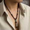 Primordial Layered Agate Pendant Necklace – Pangu Inspired Worn Look Male model wearing the Primordial Layered Agate Pendant Necklace, featuring a natural layered agate pendant with turquoise and red beads on a black hand-knotted cord, inspired by Pangu mythology