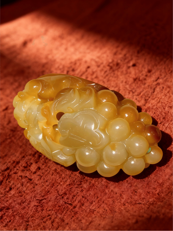 Handheld Agate Artwork titled Ring of Abundance, featuring a rounded, bead-like sculptural form carved in translucent golden agate