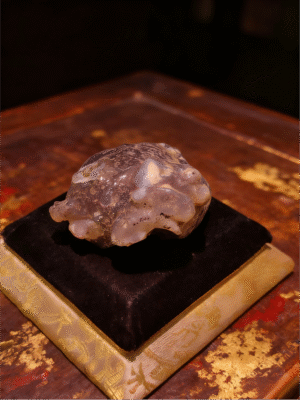 Handheld Agate Artwork titled Stone Sentinel, featuring a compact, guardian-like stone form displayed on a padded stand