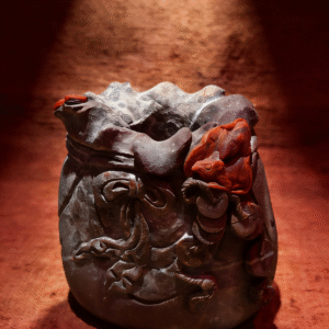 hand-carved mineral collectible titled The Treasure Pouch, featuring a sculptural agate vessel with intricate carved details and a pouch-like form displayed as a decorative object