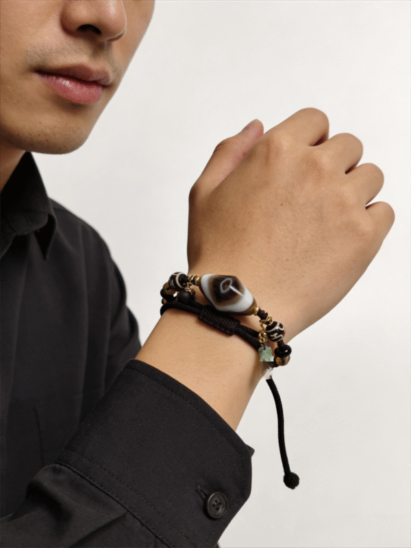 Model wearing Gonggong inspired layered agate and dzi bracelet on wrist