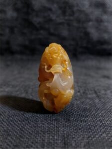 handheld agate artwork titled Amber Warden, carved from natural agate stone as a compact guardian-style collectible sculpture