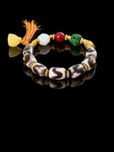 Gonggong-inspired beaded bracelet featuring Dzi beads, agate, jade, beeswax amber, and multicolored woven cord.